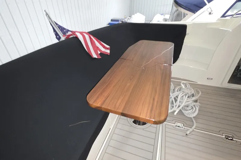 Slide: The Image of 2018 Carver C52 Coupe yacht interior with wooden table and American flag. - 24