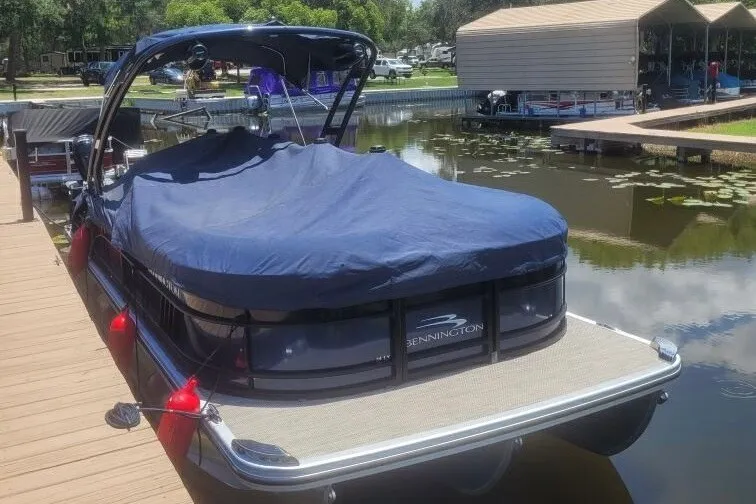 Slide: The Image of 2023 Bennington 24 LXS Swingback pontoon boat docked with cover on. - 2