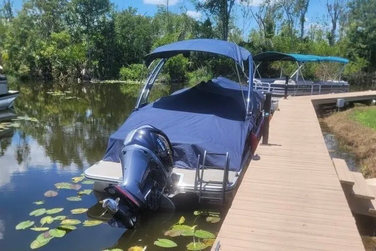 Slide: The Image of 2023 Bennington 24 LXS Swingback pontoon boat docked on a serene lake. - 5