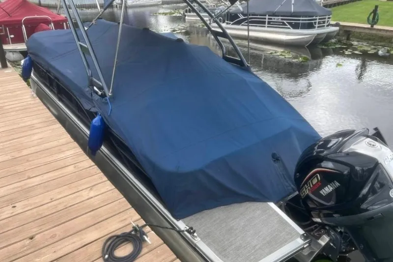 Slide: The Image of 2023 Bennington 24 LXS Swingback pontoon boat covered at dock with Yamaha outboard motor. - 4
