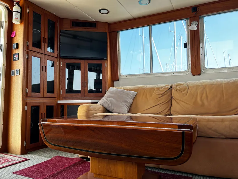 Slide: The Image of Interior of 2003 Nordic Tug 52 with beige sofa, wooden table, and mounted TV. - 45