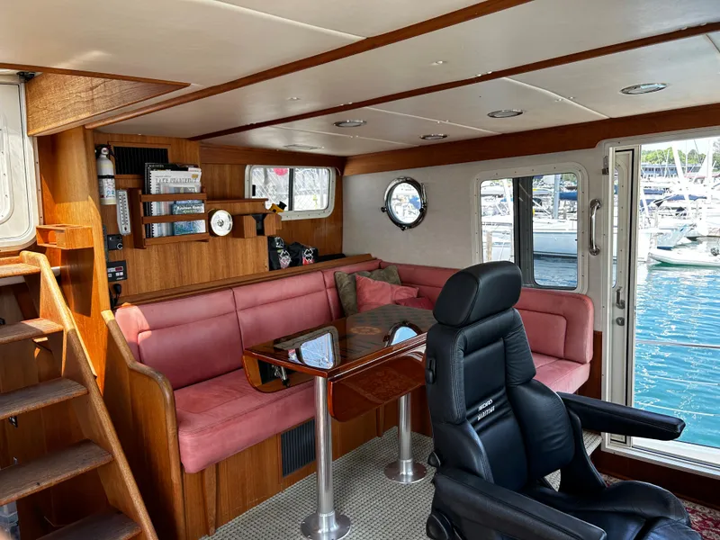 Slide: The Image of Interior of 2003 Nordic Tug 52 with pink seating, wooden accents, and marina view. - 46