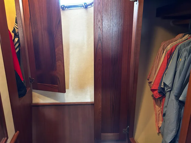 Slide: The Image of Wooden closet interior on a 2003 Nordic Tug 52, featuring hanging clothes and open doors. - 47