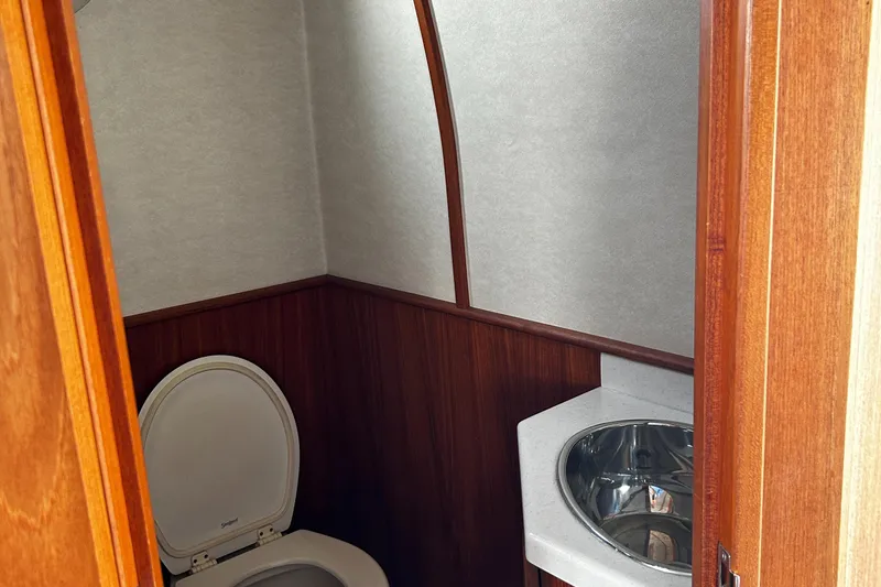 Slide: The Image of 2003 Nordic Tug 52 bathroom with wood paneling, toilet, and stainless steel sink. - 48