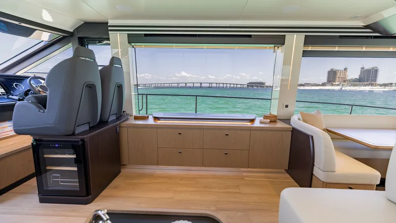 Slide: The Image of Main Salon with Ocean View The main salon of the 2027 60 Absolute Flybridge offers a stunning panoramic ocean view through expansive windows. The elegant interior features plush seating and a sleek helm station, complemented by modern cabinetry and ample natural light. This space i - 6492487