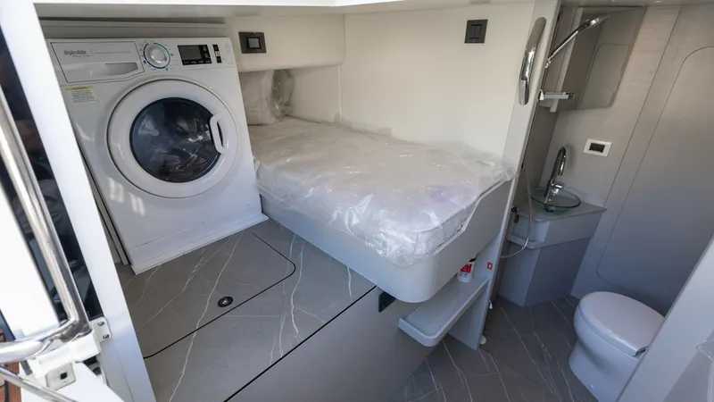 Slide: The Image of Crew Cabin with Laundry Facilities This well-appointed crew cabin on the 2027 60 Absolute Flybridge features a compact yet efficient layout. It includes a comfortable berth, integrated washer and dryer, and a private bathroom with modern fixtures. The use of high-quality materials and smar - 6492539