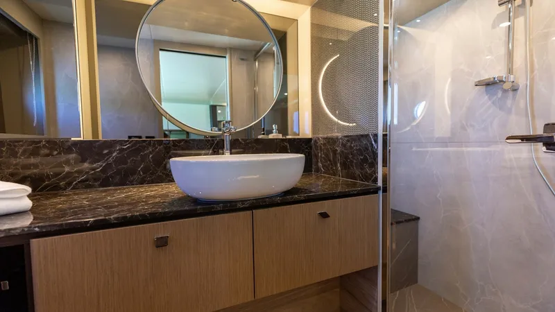 Slide: The Image of Luxury Ensuite Bathroom This elegant ensuite bathroom on the 2027 Absolute 60 Flybridge features a modern design with a sleek marble countertop and a stylish vessel sink. The spacious shower area is enclosed with clear glass, offering a luxurious and refreshing experience. Warm - 6492501