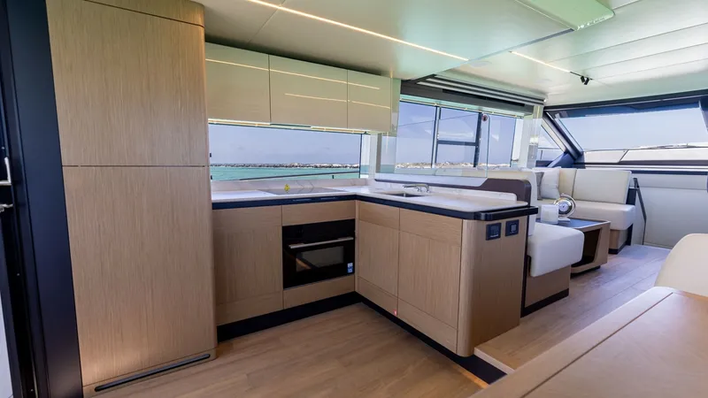 Slide: The Image of Modern Galley and Salon Area This image showcases the sleek and modern galley of the 2027 60 Absolute Flybridge. The space features high-quality wood finishes and state-of-the-art appliances, seamlessly integrated into the cabinetry. Large windows provide abundant natural light, enha - 6492480