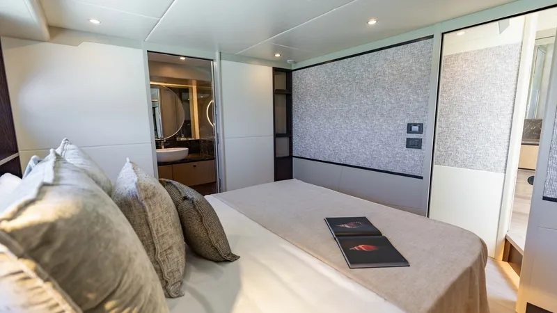 Slide: The Image of VIP Stateroom with Ensuite Access The master stateroom of the 2027 60 Absolute Flybridge offers a luxurious retreat with soft, neutral tones and elegant finishes. Plush bedding complements the modern design, creating a cozy yet sophisticated atmosphere. The ensuite bathroom is visible, fe - 6492497