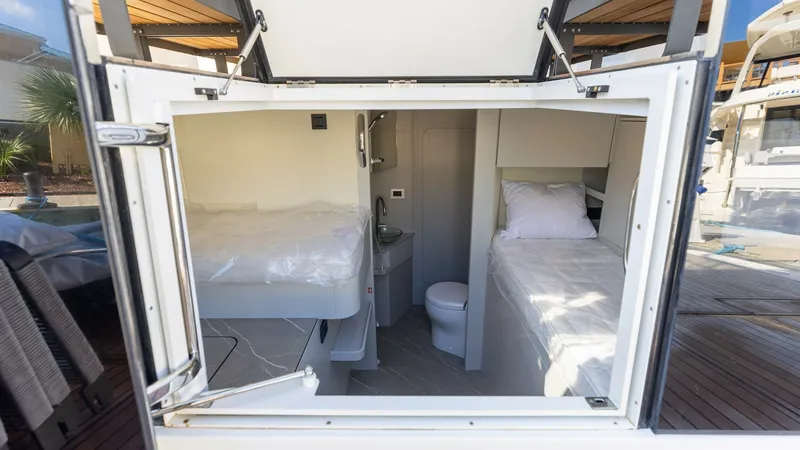 Slide: The Image of Crew Quarters with Twin Berths The crew quarters of the 2027 Absolute 60 Flybridge feature twin berths, providing ample space and comfort. The compact area includes a small sink and toilet, maximizing functionality within the limited space. Finished with high-quality materials, this ar - 6492538