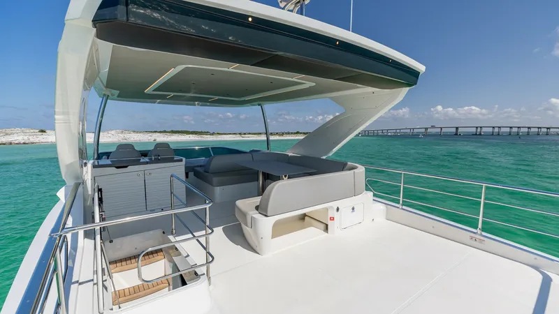 Slide: The Image of Expansive Flybridge Lounge Area The 2027 Absolute 60 Flybridge offers an expansive outdoor lounge area, perfect for entertaining and relaxation. This space features plush seating under a stylish, modern hardtop that provides shade and comfort. The panoramic views and sleek design make t - 6492521