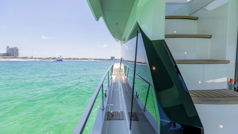 Slide: The Image of Starboard Side Deck and Staircase The starboard side deck of the 2027 Absolute 60 Flybridge offers a sleek walkway with high-gloss finishes and safety railings, leading to the foredeck. The elegant staircase, adorned with teak steps, ascends to the flybridge, showcasing thoughtful design - 6492513