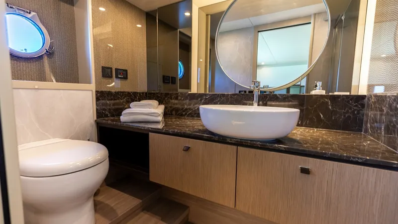 Slide: The Image of Elegant Ensuite Bathroom This luxurious ensuite bathroom on the 2027 Absolute 60 Flybridge features a sleek design with high-end finishes. The marble countertop complements the modern vessel sink, while the round mirror adds a touch of elegance. Natural light filters through the - 6492499