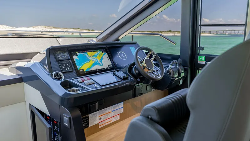 Slide: The Image of Helm Station with Navigation Display The helm station of the 2027 60 Absolute Flybridge showcases a state-of-the-art navigation display integrated into a sleek control panel. The ergonomic design includes a premium steering wheel and intuitive controls, ensuring effortless maneuverability. E - 6492489