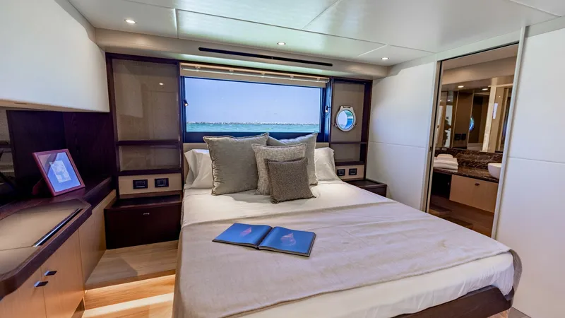 Slide: The Image of Luxurious VIP Stateroom View Experience comfort in the master stateroom of the 2027 Absolute 60 Flybridge. This serene space features a plush bed with elegant linens, surrounded by warm wood accents and soft lighting. Enjoy breathtaking ocean views through the large window, adding a - 6492496