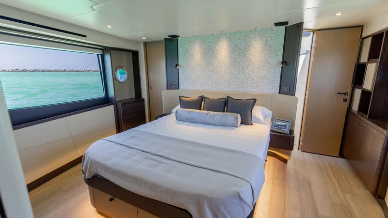 Slide: The Image of Master Stateroom with Ocean View The master stateroom of the 2027 60 Absolute Flybridge offers a serene escape with a panoramic ocean view through large windows. The room features a plush, king-size bed complemented by modern, elegant wood finishes and ambient lighting. Ample storage and - 6492476