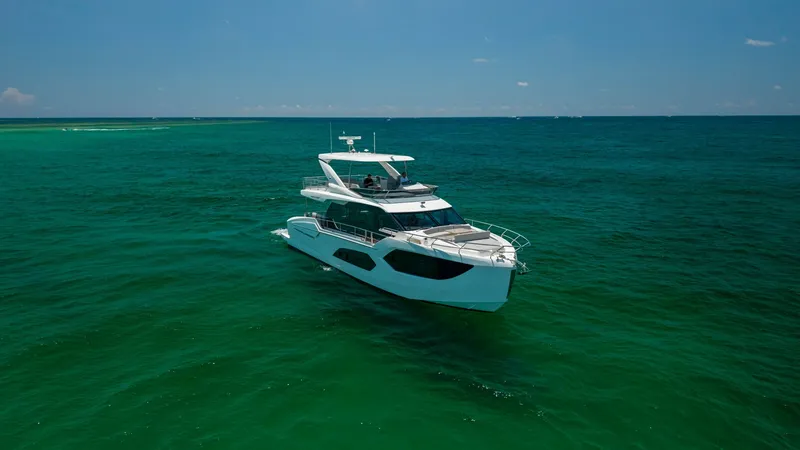 Slide: The Image of Aerial View of Flybridge Yacht This image showcases the sleek exterior of the 2027 Absolute 60 Flybridge, elegantly cutting through the pristine waters. The flybridge offers expansive views, ideal for navigating and entertaining. With its modern design and spacious layout, this yacht p - 6492548