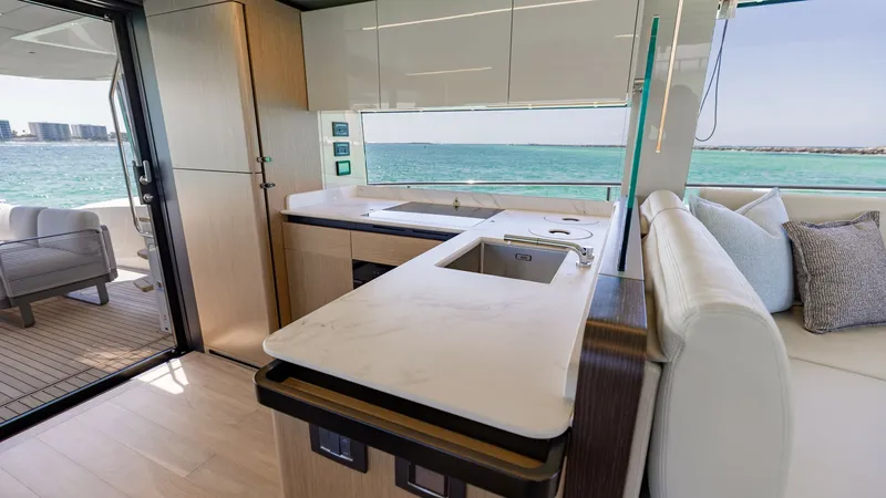 Slide: The Image of Galley with Ocean View This modern galley on the 2027 Absolute 60 Flybridge boasts sleek cabinetry and a polished countertop, offering both style and functionality. The large window provides a stunning ocean view, enhancing the open and airy feel of this space. Adjacent to the - 6492478