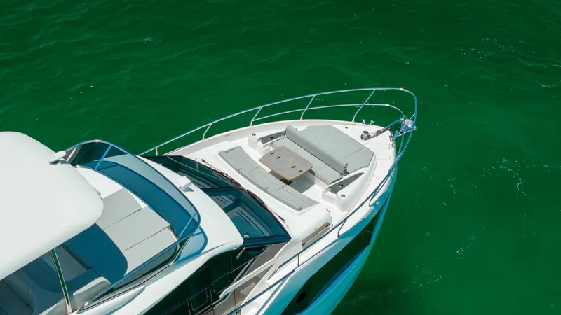 Slide: The Image of Elegant Bow Lounge Area The 2027 Absolute 60 Flybridge showcases a luxurious bow lounge with plush seating and a central table, perfect for relaxation and socializing. Surrounded by sleek stainless steel railings, this area offers safety without compromising the open-air experie - 6492552