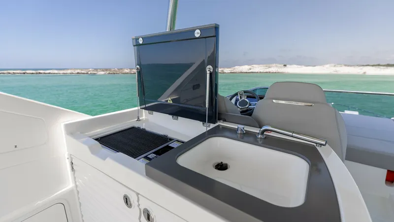 Slide: The Image of Flybridge Outdoor Kitchen and Helm The flybridge of the 2027 60 Absolute Flybridge features a sleek outdoor kitchen equipped with a grill and sink, perfect for alfresco dining. Adjacent to the kitchen is a comfortable helm station with plush seating, offering panoramic views of the water. - 6492535