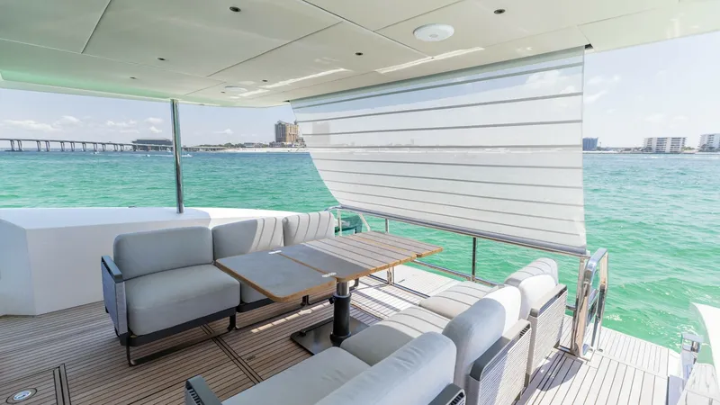Slide: The Image of Spacious Aft Deck Lounge Area The aft deck of the 2027 60 Absolute Flybridge offers a luxurious outdoor lounge with plush seating and a sleek dining table. Its retractable sunshade provides comfort and protection while enjoying panoramic ocean views. The teak decking adds a touch of e - 6492507