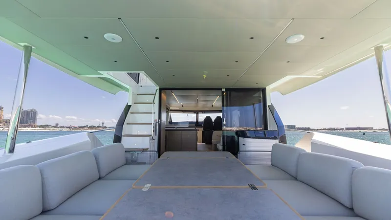 Slide: The Image of Spacious Aft Deck with Dining Area The aft deck of the 2027 60 Absolute Flybridge offers an inviting space with a large dining table surrounded by plush seating, perfect for alfresco meals. The area features a seamless connection to the indoor salon, enhancing the open and airy ambiance. O - 6492514
