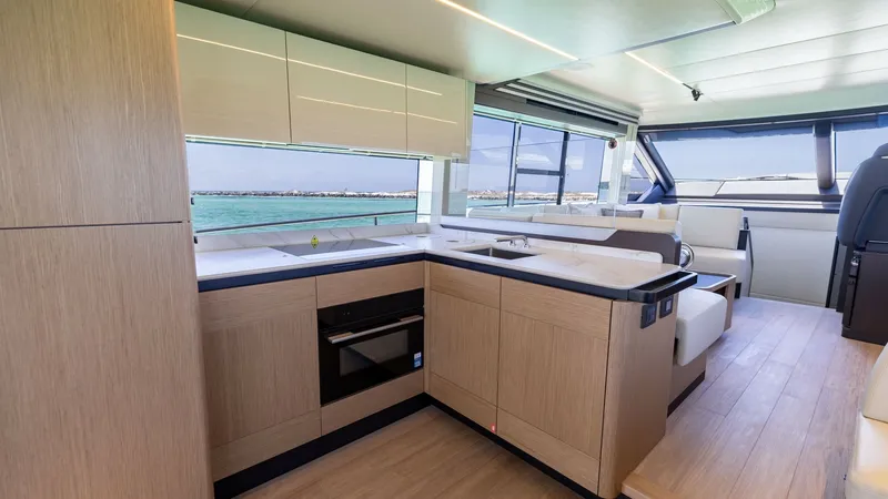 Slide: The Image of Modern Galley with Ocean Views This elegant galley on the 2027 Absolute 60 Flybridge features sleek cabinetry and top-of-the-line appliances, providing a seamless culinary experience. The expansive windows offer stunning ocean views, filling the space with natural light. The open layou - 6492479