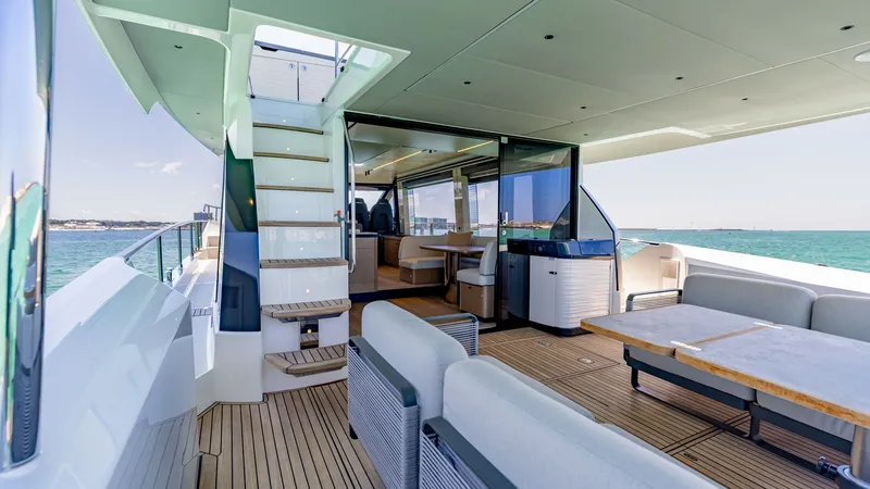 Slide: The Image of Spacious Aft Deck with Seating Area The aft deck of the 2027 60 Absolute Flybridge showcases a luxurious and spacious seating area, perfect for entertaining guests. The elegant teak flooring complements the modern design, while the staircase leads seamlessly to the upper flybridge. Large gl - 6492474
