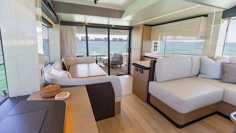 Slide: The Image of Spacious Interior Salon with Ocean Views This inviting interior salon of the 2027 60 Absolute Flybridge boasts expansive ocean views through large windows and a sliding glass door. The elegant layout features plush, contemporary seating and a stylish dining area, creating a perfect space for rel - 6492486