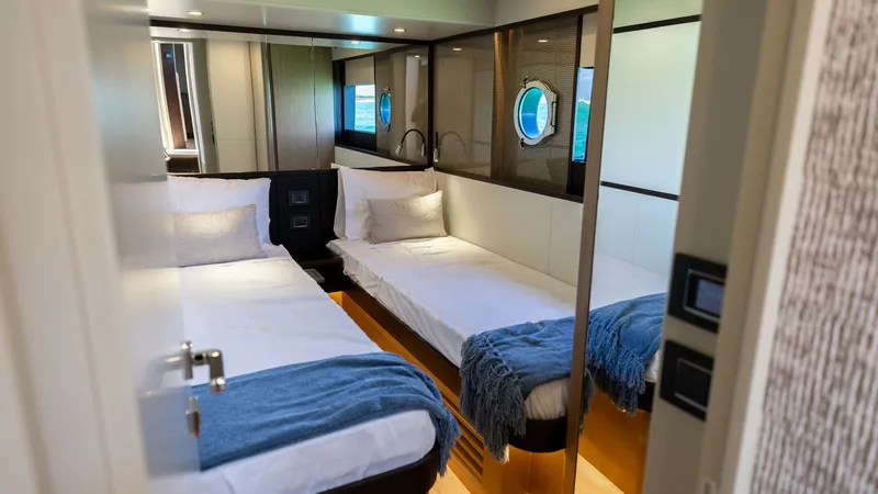 Slide: The Image of Twin Guest Stateroom This inviting twin guest stateroom on the 2027 60 Absolute Flybridge combines comfort and elegance. Featuring two well-appointed single beds, the space is accentuated by sleek, modern finishes and warm lighting. A large porthole offers natural light and a - 6492502