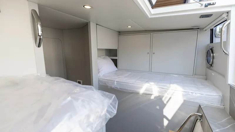 Slide: The Image of Guest Cabin with Twin Beds This inviting guest cabin on the 2027 60 Absolute Flybridge features twin beds with sleek, modern finishes. Natural light floods the space through a well-placed skylight and a side window, creating a bright and airy ambiance. Ample storage is provided by - 6492541