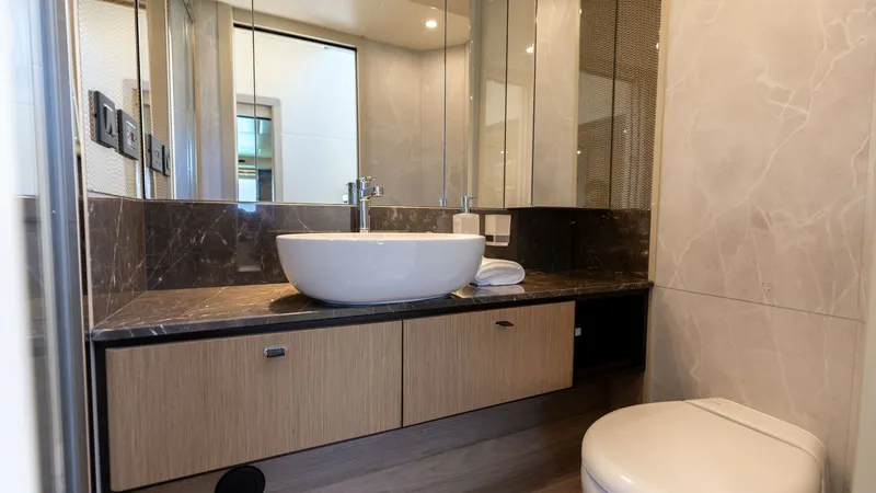 Slide: The Image of Luxurious Ensuite Bathroom This elegant ensuite bathroom on the 2027 Absolute 60 Flybridge features a sleek vessel sink atop a polished marble countertop. The space is enhanced by mirrored cabinetry, providing ample storage and a sense of openness. High-end fixtures and soft ambien - 6492504