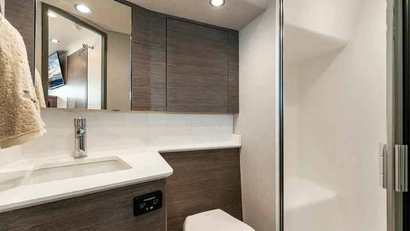 Slide: The Image of Modern Yacht Bathroom Interior - Valhalla 55 Sport Yacht This sleek bathroom on the 2027 Valhalla Boatworks 55 SY features contemporary wood paneling and elegant fixtures. The compact layout maximizes space with a stylish vanity, integrated sink, and ample storage in overhead cabinets. The soft lighting and cle - 6332936