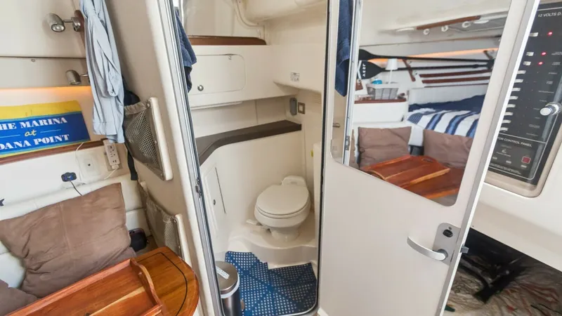 Slide: The Image of 2006 Grady-White 330 Express - "POLE POSITION": Compact Cabin with Head and Seating This image showcases the versatile cabin of the 2006 Grady-White 330 Express. The space features a well-appointed head with a toilet and practical storage, all set within a neatly designed compartment. Adjacent to the head, there's cozy seating, offering - 6572959