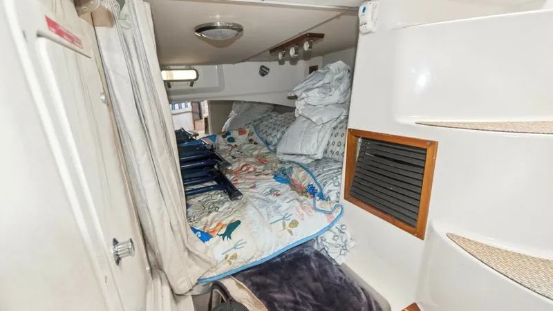 Slide: The Image of 2006 Grady-White 330 Express - "POLE POSITION": V-Berth Cabin with Bedding This cozy V-berth cabin on the 2006 Grady-White 330 Express features a comfortable sleeping area with floral bedding and ample pillows, providing a welcoming retreat. The cabin is equipped with practical storage options and soft lighting, enhancing functi - 6572961