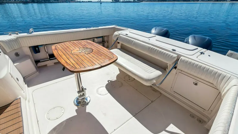 Slide: The Image of 2006 Grady-White 330 Express - "POLE POSITION": Spacious Aft Deck with Seating The aft deck of the 2006 Grady-White 330 Express features ample seating with cushioned benches, ideal for relaxation and socializing. A beautifully crafted wooden table with an intricate design serves as the centerpiece, offering a perfect spot for dining - 6572954