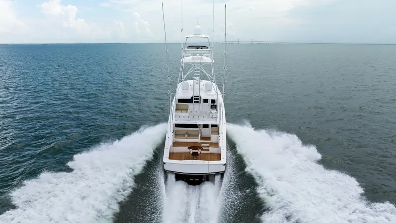 Slide: The Image of Aerial Aft View Underway The 2021 Viking 72 Enclosed Bridge showcases its sleek design as it powers through open waters. The spacious aft deck is visible, offering ample seating and a perfect view for fishing or leisure. The yacht's powerful engines create an impressive wake, hig - 7377966