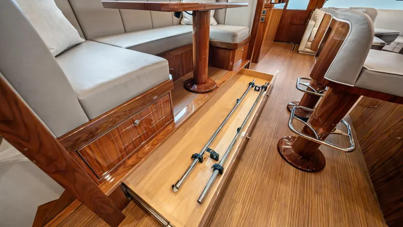 Slide: The Image of Elegant Salon Seating with Storage This image showcases the sophisticated salon seating area on the Viking 72 Enclosed Bridge. The polished wood finishes and plush seating create a luxurious and inviting atmosphere. A clever under-seat storage compartment provides convenient access to rods - 7377901
