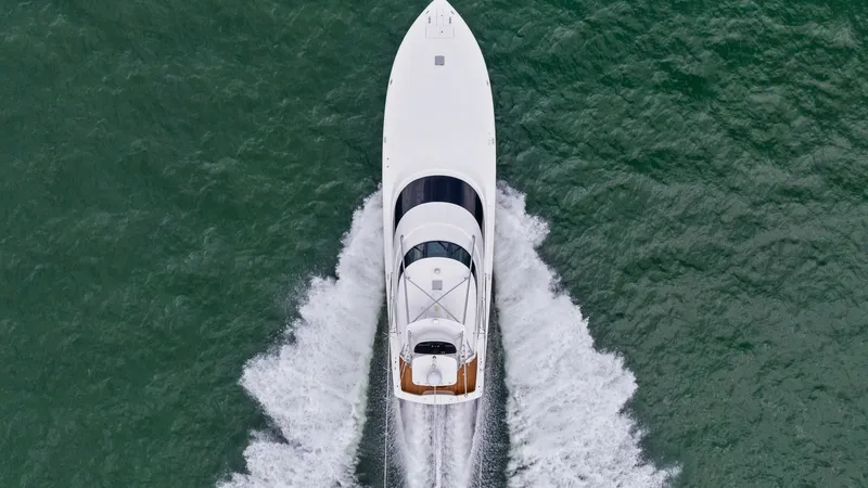 Slide: The Image of Aerial View of Viking 72 Enclosed Bridge This striking aerial shot captures the sleek design and powerful presence of the 2021 Viking 72 Enclosed Bridge. The vessel cuts gracefully through the water, showcasing its streamlined hull and spacious upper deck. The elegant design and impressive wake - 7377968