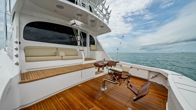 Slide: The Image of Spacious Aft Deck with Seating The aft deck of the 2021 Viking 72 Enclosed Bridge features luxurious teak flooring and a well-appointed seating area, perfect for relaxation or entertaining. A polished fighting chair is centrally positioned, showcasing the yacht's sportfishing pedigree. - 7377942