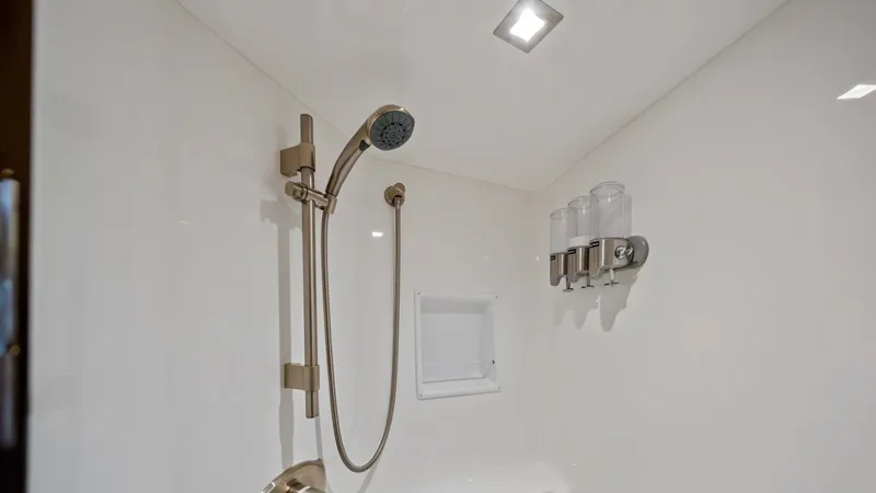 Slide: The Image of Luxury Shower with Modern Fixtures This image showcases the luxurious shower area aboard the 2021 Viking 72 Enclosed Bridge. The space features sleek, modern fixtures including a handheld showerhead and built-in dispensers for convenience. The high-gloss finish and recessed lighting create - 7377921