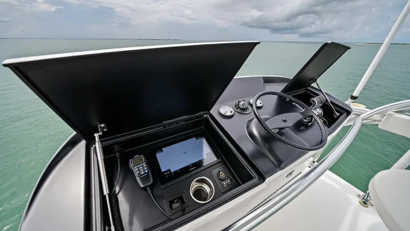 Slide: The Image of Flybridge Helm Station Overview This image showcases the helm station on the flybridge of the 2021 Viking 72 Enclosed Bridge. The station features a sleek steering wheel, advanced navigation displays, and communication equipment, all housed in a modern console design. The open-air view - 7377878