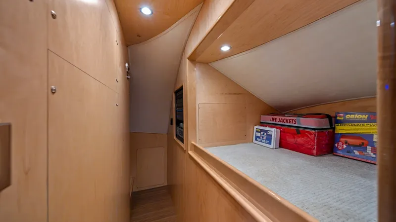 Slide: The Image of Lower Deck Storage Area This image showcases the lower deck storage area of the 2021 Viking 72 Enclosed Bridge. The space is designed with efficiency in mind, featuring a sleek wood finish and built-in shelving for organized storage. Recessed lighting enhances visibility and acc - 7377903