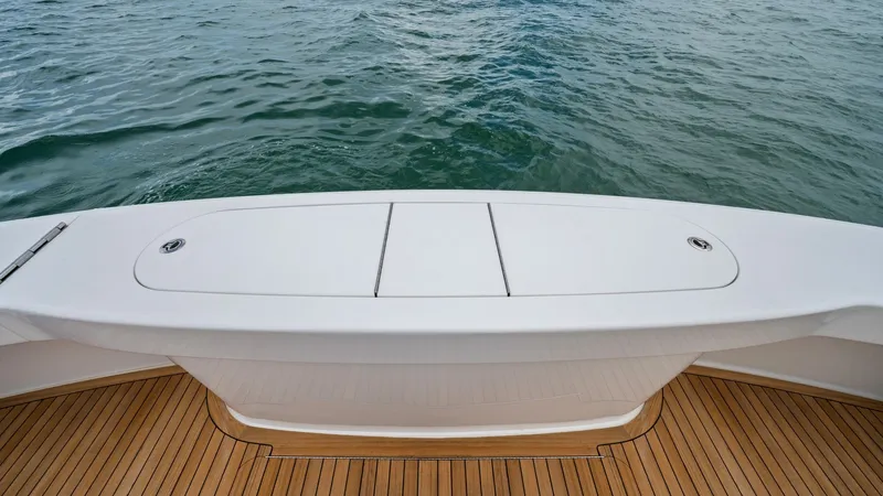 Slide: The Image of Aft Deck with Teak Flooring The aft deck of the 2021 Viking 72 Enclosed Bridge showcases elegant teak flooring, providing a warm and inviting ambiance. This spacious area is ideal for relaxation or fishing, featuring a sleek, integrated storage compartment. The seamless design and s - 7377946