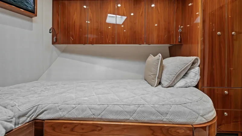 Slide: The Image of Guest Stateroom with Wood Cabinetry This guest stateroom on the 2021 Viking 72 Enclosed Bridge features a comfortable berth with luxurious bedding. The high-gloss wood cabinetry provides ample storage while adding a touch of elegance. Soft lighting and modern fixtures create a warm and invi - 7377919