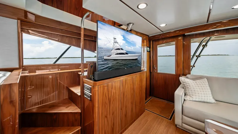 Slide: The Image of Salon with Entertainment Center The salon of the 2021 Viking 72 Enclosed Bridge showcases a luxurious entertainment area with a large flat-screen TV and elegant wood finishes. Expansive windows provide panoramic views, enhancing the spaciousness and inviting natural light. The built-in - 7377889