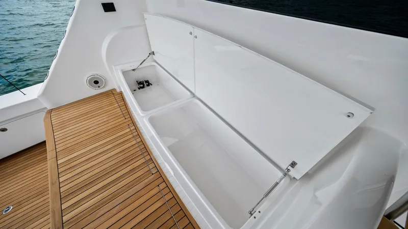 Slide: The Image of Aft Deck Storage Compartment This image showcases the spacious storage compartment on the aft deck of the 2021 Viking 72 Enclosed Bridge. The compartment features a sleek, white finish and is designed for easy access, perfect for storing gear or catch. The teak decking adds a touch o - 7377936