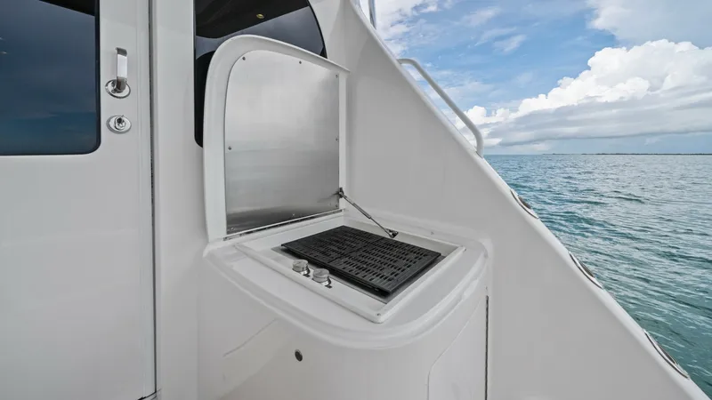 Slide: The Image of Outdoor Grill Station on Deck This image features the outdoor grill station on the deck of the 2021 Viking 72 Enclosed Bridge. The sleek, integrated design offers a convenient space for outdoor cooking, complete with a lift-up cover for protection. Positioned with a stunning ocean vie - 7377938