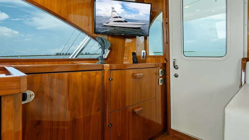 Slide: The Image of Enclosed Bridge Interior with Wood Finish This image showcases the elegant interior of the Viking 72 Enclosed Bridge, featuring rich wood cabinetry and a sleek design. The space is equipped with a mounted flat-screen TV, adding a touch of modern luxury. Large windows offer expansive views, enhanc - 7377882