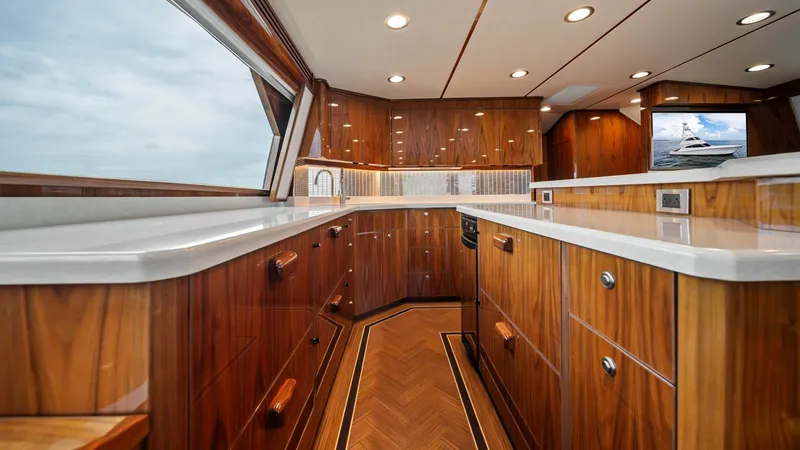 Slide: The Image of Luxurious Galley with Wood Finish This elegant galley on the 2021 Viking 72 Enclosed Bridge features exquisite wood cabinetry and sleek countertops, offering ample storage and workspace. The rich wood tones and polished finishes create a warm and inviting atmosphere, complemented by reces - 7377894